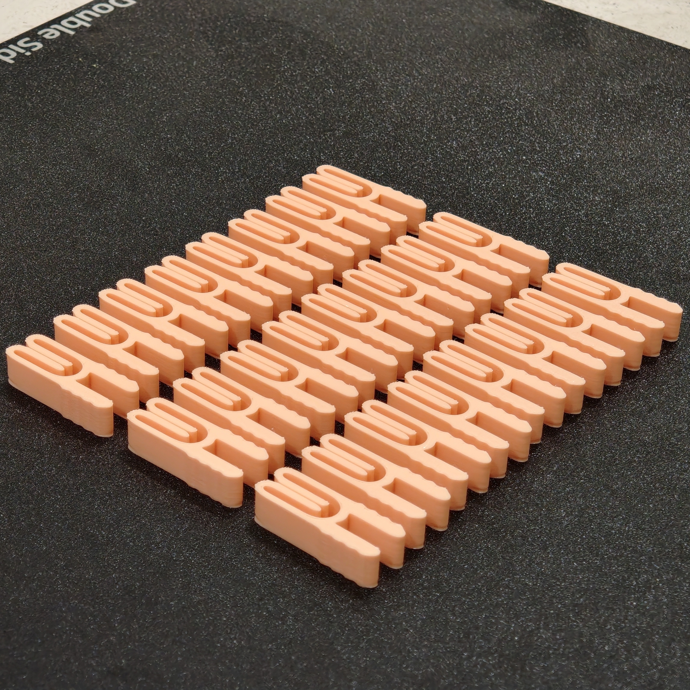 Petite série de pinces de fermeture imprimées en 3D, alignées sur le plateau d'impression